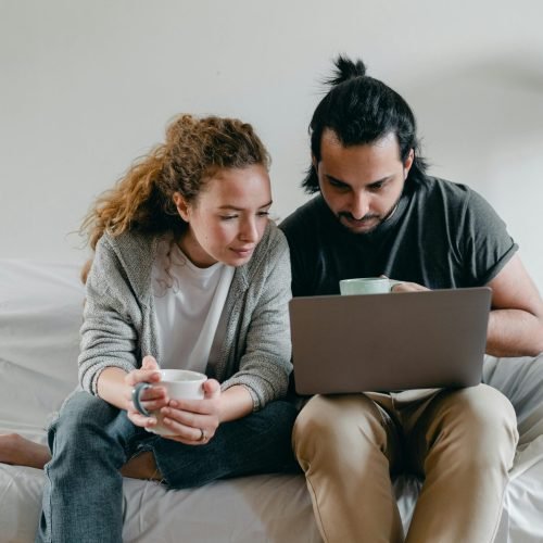 Concentrated couple browsing laptop on sofa